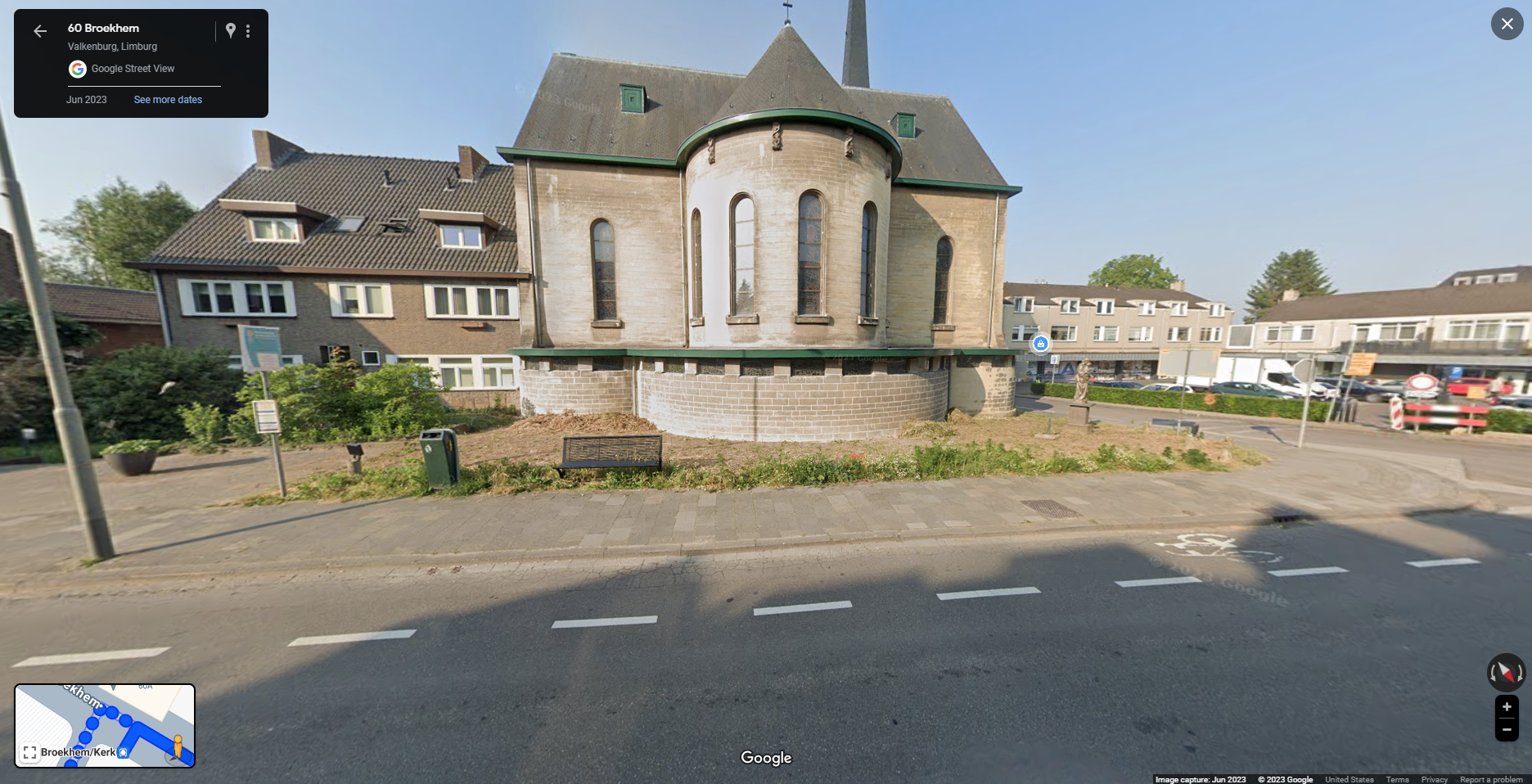 This image shows a Google Street View capture from June 2023 of 60 Broekhem in Valkenburg, Limburg, Netherlands. The focus is on a church building with a round outcropping and a unique architectural style, featuring arched windows, a green trim, and gray roof. The church is attached to a two story residential building to the left. There is a bench and a small garden area in front of the building, along with a street and sidewalk in the foreground. Surrounding the church are residential buildings and some construction work visible in the distance on the right. The map inset at the bottom-left shows the nearby area and streets, marking the location as Broekhem/Kerk.